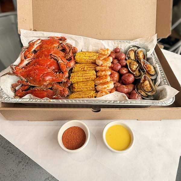 Cameron's Seafood Philly takeout box with crabs, corn, shrimp, mussels, potatoes, and dipping sauces.
