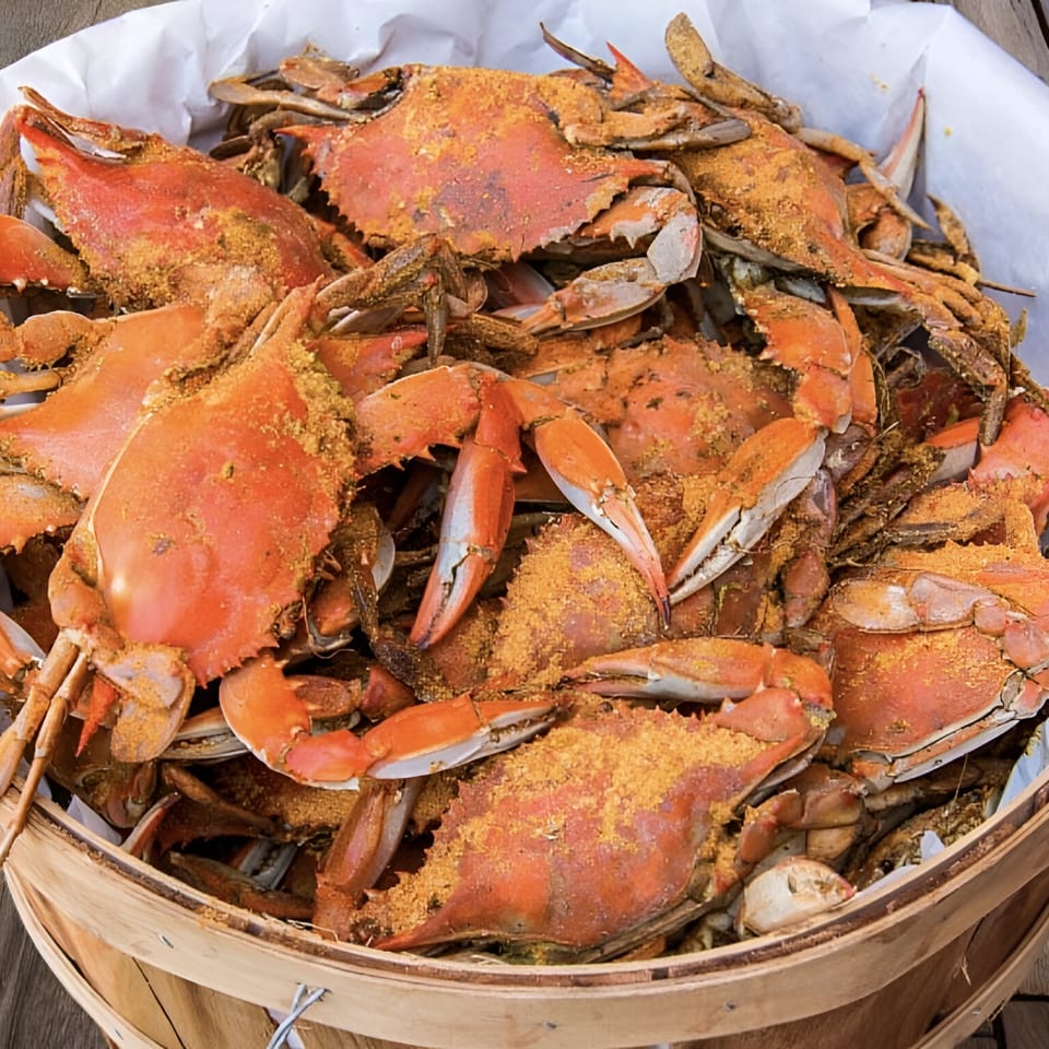 A wooden bushel basket overflowing with steamed blue crabs seasoned with Old Bay, from Cameron's Seafood Philly.